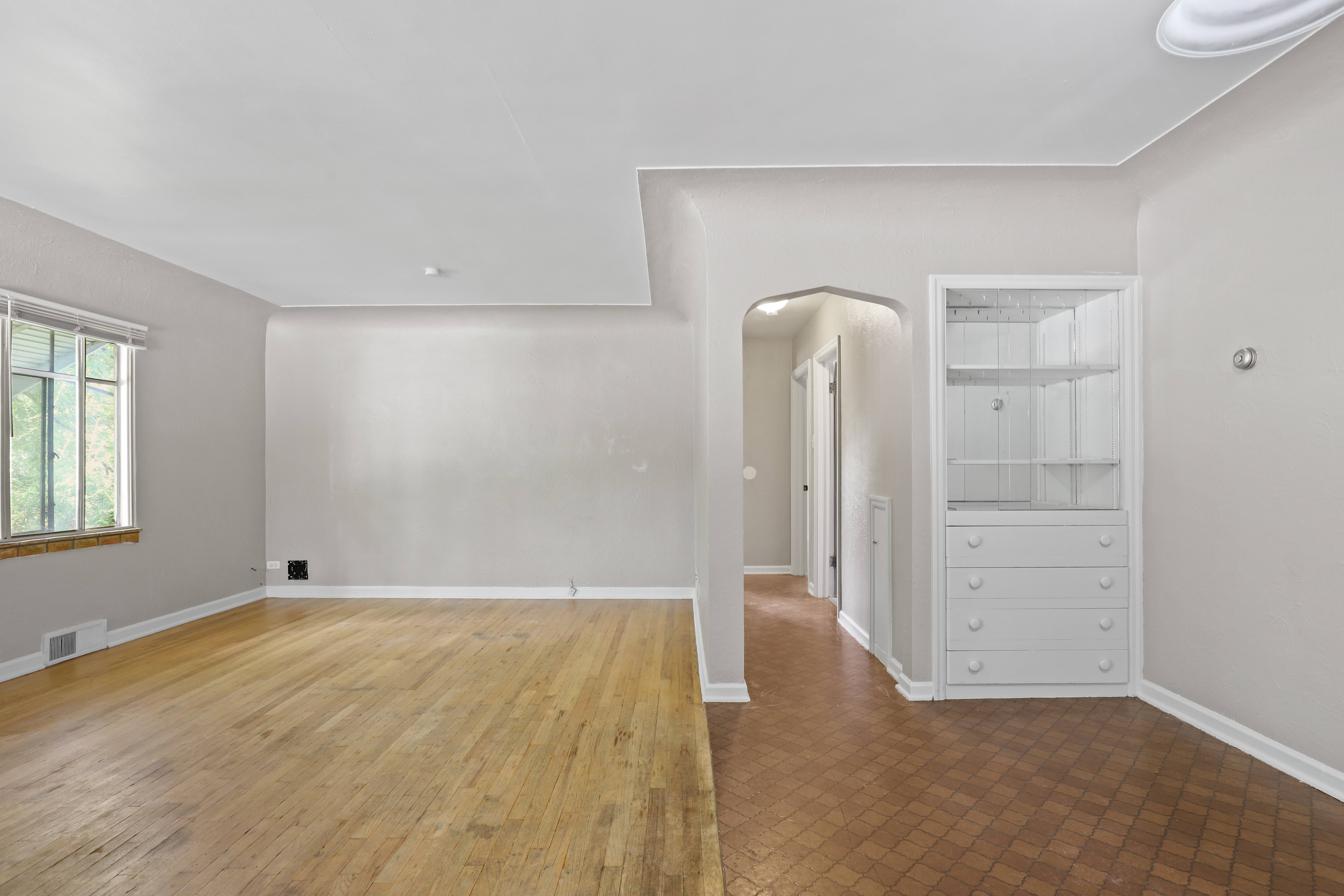 a living room with white walls and wooden floors and a white closet